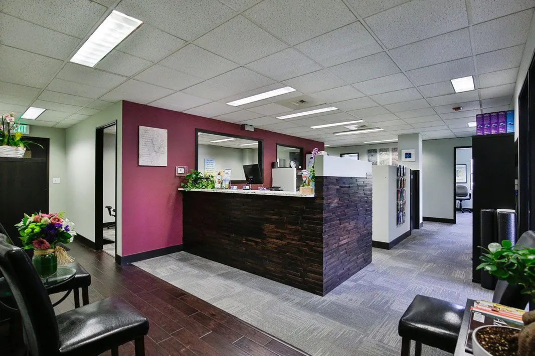 Atlas Chiropractic front desk and waiting area with a magenta accent wall